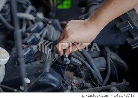 Close up of a hand of woman is open the engine oil pan cover Close up of a hand of woman is open the engine oil pan cover 142178712
