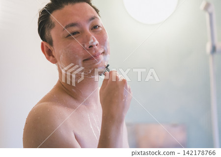 一位40歲的男子在洗澡時刮鬍子。 一位40歲的男子在洗澡時刮鬍子。 142178766