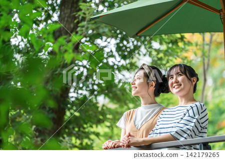 Young Asian woman relaxing on the wooden deck of a pension cottage cabin Young Asian woman relaxing on the wooden deck of a pension cottage cabin 142179265