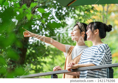一位年輕的亞洲女性在養老金/小屋/小屋的木甲板上放鬆 一位年輕的亞洲女性在養老金/小屋/小屋的木甲板上放鬆 142179266