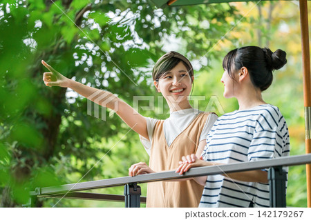 一位年輕的亞洲女性在養老金/小屋/小屋的木甲板上放鬆 一位年輕的亞洲女性在養老金/小屋/小屋的木甲板上放鬆 142179267