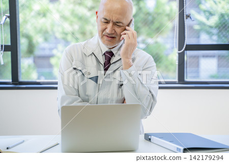 A man in work clothes doing desk work A man in work clothes doing desk work 142179294