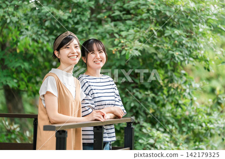 一位年輕的亞洲女性在養老金/小屋/小屋的木甲板上放鬆 一位年輕的亞洲女性在養老金/小屋/小屋的木甲板上放鬆 142179325