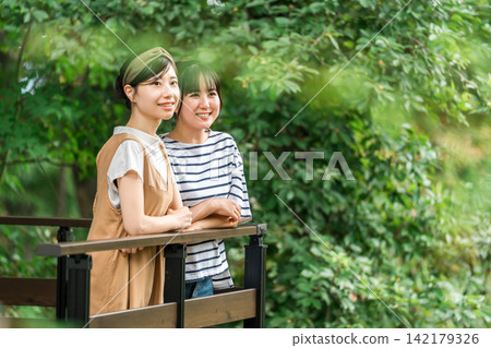 一位年輕的亞洲女性在養老金/小屋/小屋的木甲板上放鬆 一位年輕的亞洲女性在養老金/小屋/小屋的木甲板上放鬆 142179326
