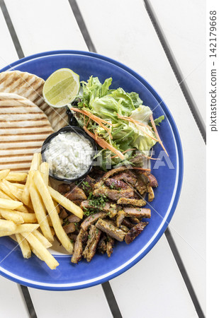 sliced grilled lamb chop with fries and Tzatziki in greek outdoor cafe sliced grilled lamb chop with fries and Tzatziki in greek outdoor cafe 142179668