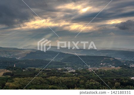 A mountain range covered in the wild woods illuminated by the golden light of the setting sun. A natural Park reserve or hunting grounds. Recreational outdoor tourism 142180331