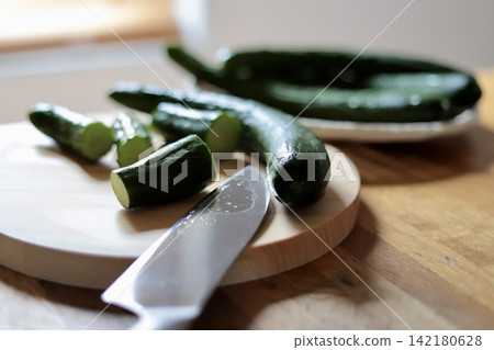 Fresh cucumbers from the home garden being cut on a cypress cutting board. 142180628