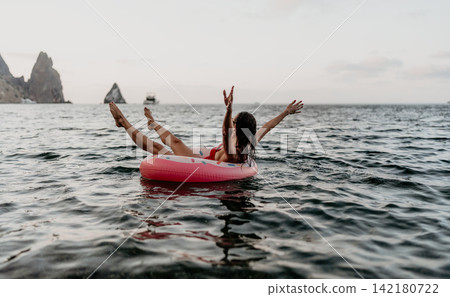 Woman, sea, inflatable. Relaxing woman floating on a donut ring in calm sea, enjoying summer freedom Woman, sea, inflatable. Relaxing woman floating on a donut ring in calm sea, enjoying summer freedom 142180722