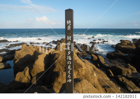 A stone monument marking "A Cape with a Spectacular View of Sunrise and Sunset" stands on a rocky cape in a park near Nojimazaki Lighthouse in Chiba Prefecture, and the blue sea. 142182011