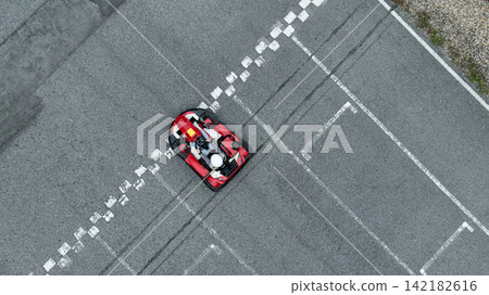Aerial view Go kart racer cross the finish line, Go kart at circuit start and finish line, Top view race go kart track. Aerial view Go kart racer cross the finish line, Go kart at circuit start and finish line, Top view race go kart track. 142182616