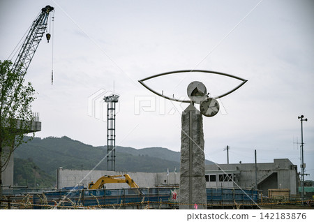 Under a cloudy sky, the clock on a monument, frozen in time by the tsunami, stands amidst the scenery of the reconstruction work site. Under a cloudy sky, the clock on a monument, frozen in time by the tsunami, stands amidst the scenery of the reconstruction work site. 142183876