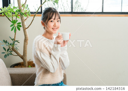 小學和中學的女孩們在家裡的客廳喝熱飲 142184316