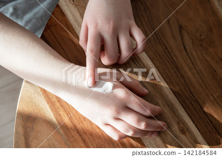Skincare concept. Hand of girl apply the moisturizing cream on her dry skin. Bodycare every day. Skincare concept. Hand of girl apply the moisturizing cream on her dry skin. Bodycare every day. 142184584