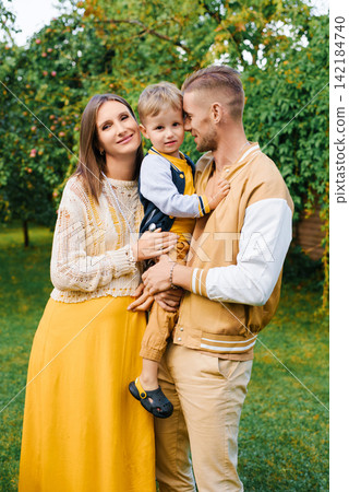 Parents Hugging Child With Joy In Green Garden Parents Hugging Child With Joy In Green Garden 142184740