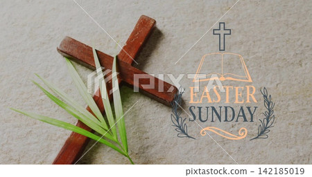 Placing wooden cross angled on beige stone, palm frond overlaying arm and EASTER SUNDAY graphic. Stilllife, flatlay, sacred, reverent, typography, inscription, concrete 142185019