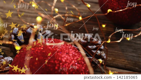 Glittering red ornament occupying foreground on wooden plank, with fairy lights, pinecone, joy text Glittering red ornament occupying foreground on wooden plank, with fairy lights, pinecone, joy text 142185065