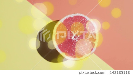Displaying halved grapefruit with pink segments on two-tone backdrop, casting shadow and bokeh 142185118