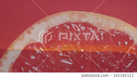 Displaying halved grapefruit showing translucent pulp and rind in studio, with sunset horizon Displaying halved grapefruit showing translucent pulp and rind in studio, with sunset horizon 142185121