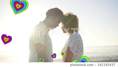 Standing couple touching foreheads at beach, wearing lace dress and light shirt, hearts, sun flare. Silhouette, romance, backlit, sunset, coastline, intimacy, colorful Standing couple touching foreheads at beach, wearing lace dress and light shirt, hearts, sun flare. Silhouette, romance, backlit, sunset, coastline, intimacy, colorful 142185437