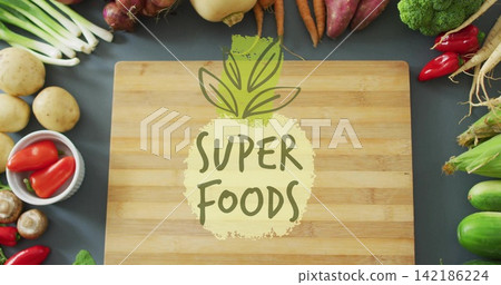 Showing wooden board featuring SUPER FOODS graphic on dark tabletop, with bowl holding red peppers Showing wooden board featuring SUPER FOODS graphic on dark tabletop, with bowl holding red peppers 142186224