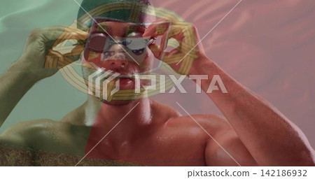Adjusting shirtless man in swim cap holding mirrored goggles showing droplets in studio flag emblem Adjusting shirtless man in swim cap holding mirrored goggles showing droplets in studio flag emblem 142186932