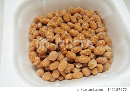 A close-up of natto, a fermented food in a white pack. A close-up of natto, a fermented food in a white pack. 142187372