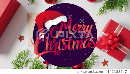 Showing badge reading Merry-Christmas with Santa hat on white table, with red gifts, evergreen Showing badge reading Merry-Christmas with Santa hat on white table, with red gifts, evergreen 142188347