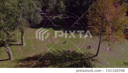 Displaying aerial HUD overlay over grassy clearing at park, showing wooden bench and green object Displaying aerial HUD overlay over grassy clearing at park, showing wooden bench and green object 142188396