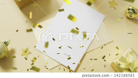 Resting blank white card sitting on cream envelope on beige tabletop, with falling gold confetti Resting blank white card sitting on cream envelope on beige tabletop, with falling gold confetti 142188581