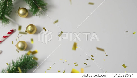 Showing holiday display on white table with evergreen gold baubles candy cane confetti, copy space 142188584