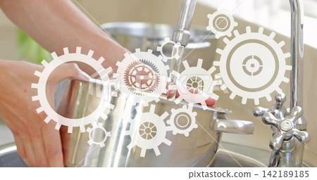 Person washing steel pot at sink under running faucet, rinsing, prepping meal with gear overlay Person washing steel pot at sink under running faucet, rinsing, prepping meal with gear overlay 142189185