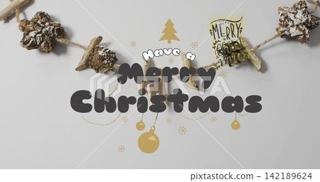 Featuring central Merry Christmas text sitting on pinecone garland on gray table, gold ornaments Featuring central Merry Christmas text sitting on pinecone garland on gray table, gold ornaments 142189624