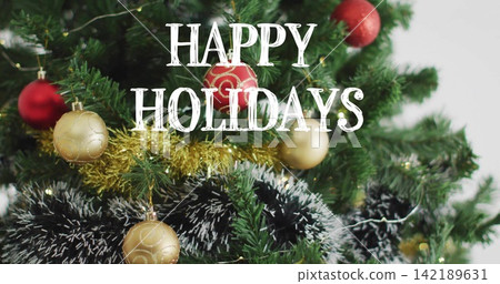 Filling frame evergreen tree glowing with string lights at home, with gold tinsel, red baubles Filling frame evergreen tree glowing with string lights at home, with gold tinsel, red baubles 142189631