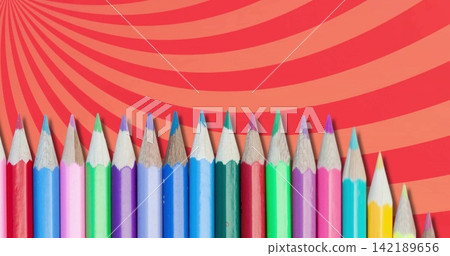 Displaying lined row of colored wooden pencils with sharpened tips on table, red-orange swirl board Displaying lined row of colored wooden pencils with sharpened tips on table, red-orange swirl board 142189656