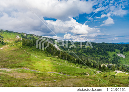 Breathtaking summer day in wild mountain with coniferous forest and green slopes. Mountain landscape with meadow. Mountainous landscape with cloudy sky. Scenic green hill mountain Breathtaking summer day in wild mountain with coniferous forest and green slopes. Mountain landscape with meadow. Mountainous landscape with cloudy sky. Scenic green hill mountain 142190361
