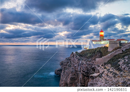 Cabo de Sao Vicente lighthouse in evening light above clifftop buildings Cabo de Sao Vicente lighthouse in evening light above clifftop buildings 142190831