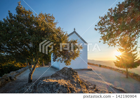 White chapel on a hill during dawn in a scenic valley landscape. 142190904