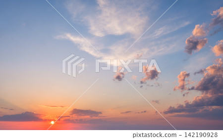 Dramatic sunset sky with vibrant colors and fluffy clouds over a serene horizon 142190928