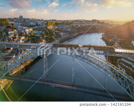 Sunrise drone view of tram on Dom Luis I Bridge with old town skyline Sunrise drone view of tram on Dom Luis I Bridge with old town skyline 142191104