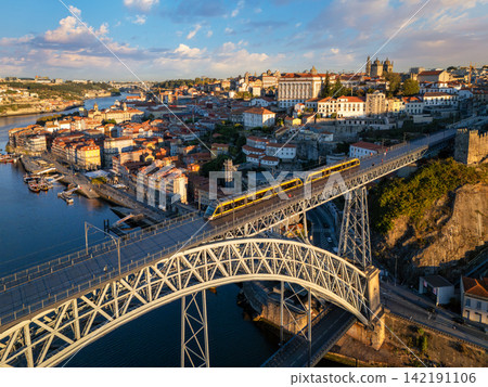 Sunrise drone view of tram on Dom Luis I Bridge with hillside streets Sunrise drone view of tram on Dom Luis I Bridge with hillside streets 142191106