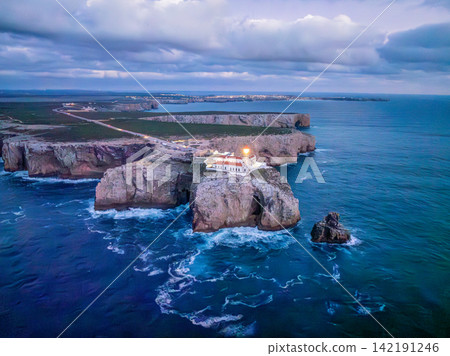 Aerial view of Cabo de Sao Vicente lighthouse in evening light by cape road Aerial view of Cabo de Sao Vicente lighthouse in evening light by cape road 142191246