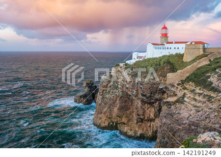 Cabo de Sao Vicente lighthouse at sunrise with clouds over the ocean Cabo de Sao Vicente lighthouse at sunrise with clouds over the ocean 142191249