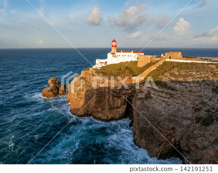 Cabo de Sao Vicente lighthouse at sunrise on a sunlit cliff edge Cabo de Sao Vicente lighthouse at sunrise on a sunlit cliff edge 142191251