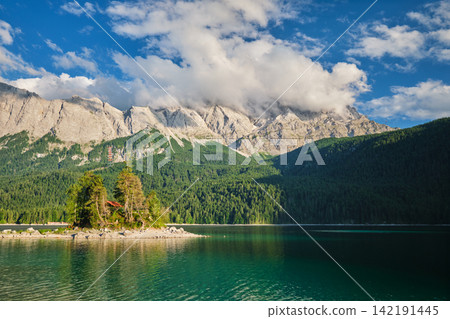 Lone island in Eibsee lake with clouds over Zugspitze in Bavaria Germany Lone island in Eibsee lake with clouds over Zugspitze in Bavaria Germany 142191445
