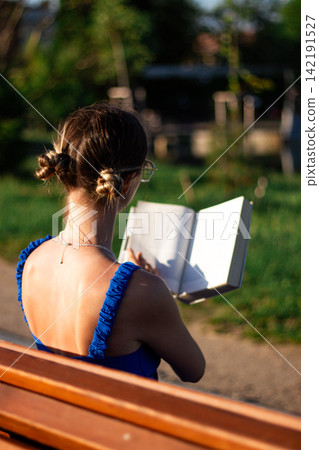 Girl with book on park bench. Conscious gadget break. Harmony with nature and literature. Slow living at its best. Seasonal ritual of summer reading outdoors. Book lovers day Girl with book on park bench. Conscious gadget break. Harmony with nature and literature. Slow living at its best. Seasonal ritual of summer reading outdoors. Book lovers day 142191527