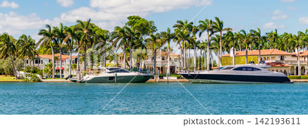 Waterfront landscape with motorboat. Vacation in summer. Luxury waterfront building. Summer vacation. Yacht in luxury residential area. Residential waterfront apartment with boat. Private harbor Waterfront landscape with motorboat. Vacation in summer. Luxury waterfront building. Summer vacation. Yacht in luxury residential area. Residential waterfront apartment with boat. Private harbor 142193611