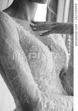 Bride in lace wedding dress with long sleeves touching chest in elegant black and white portrait. Bride in lace wedding dress with long sleeves touching chest in elegant black and white portrait. 142193929