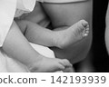 Close up of newborn baby feet resting on adult leg in black and white artistic style. 142193939