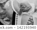 Close up of newborn baby feet in traditional white embroidered clothing during a baptism ceremony. 142193940