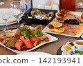 Gourmet appetizer platter with colorful vegetable rolls and smoked salmon on a banquet table. 142193941